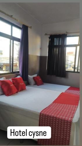 Habitación de hotel con cama con almohadas rojas en HOTEL CYSNE, en Sobral