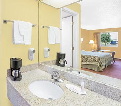 baño con lavabo, espejo y cama en Travel Inn North Little Rock, en North Little Rock