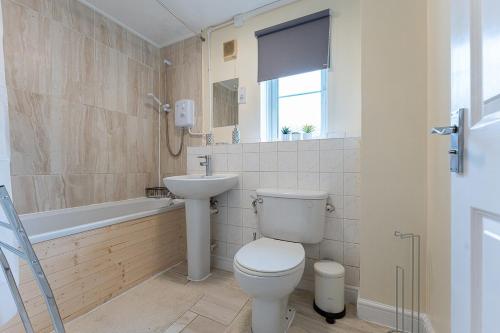 a bathroom with a toilet and a sink and a tub at The Mullard in Hackbridge
