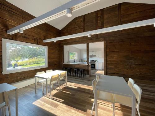 uma sala de jantar com paredes e mesas de madeira e uma janela em La Belle Excuse em Saint-Joachim