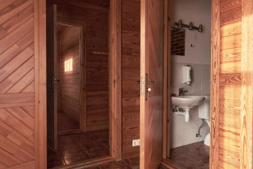 a bathroom with a wooden door and a sink at Juku Dzirnavas in Zutēni