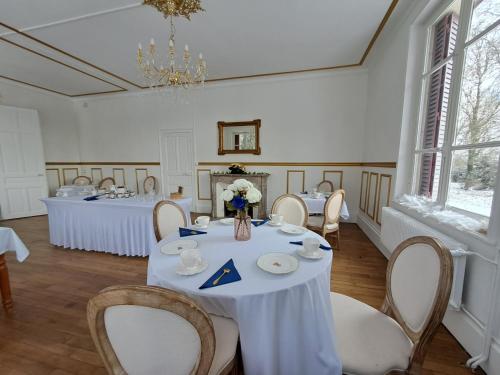 a dining room with white tables and chairs and a chandelier at Château des Aulnes 