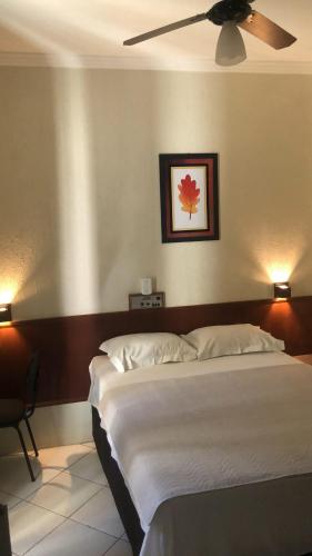 a bedroom with a large bed with a ceiling fan at Hotel de Minas in Caxambu