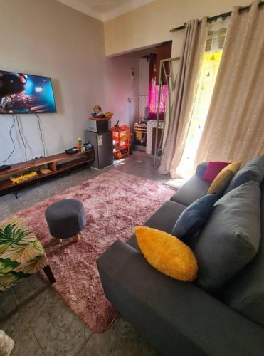 a living room with a gray couch and a flat screen tv at Tizo comfort homes in Wakiso
