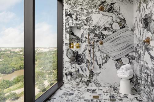 a bathroom with a stone wall with a toilet and a window at Thompson Houston, by Hyatt in Houston