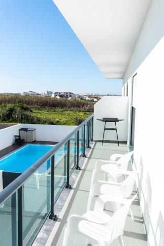 d'un balcon avec des chaises blanches, une table et une piscine. dans l'établissement SAL Baleal, à Baleal