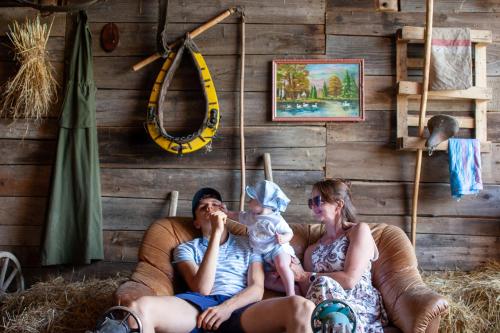 a man and woman sitting on a couch with a baby at Ranczo Molikówka gospodarstwo z Końmi Sauna i Banią in Siołkowa