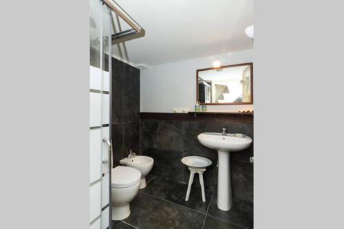 y baño con 2 aseos, lavamanos y espejo. en Il Pozzo di Santa Teresa, en Catania