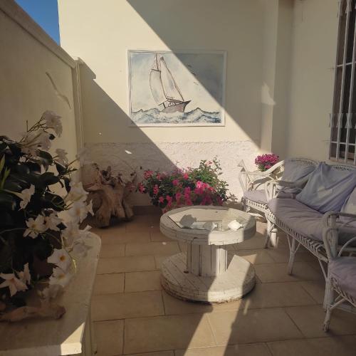 een patio met een tafel, stoelen en bloemen bij YSOR CASA VACANZE in Casalabate