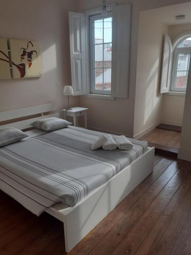 a white bedroom with a large bed with two pillows at Casa Aveiro Praça Do Peixe in Aveiro