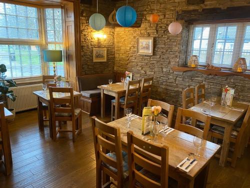 a restaurant with wooden tables and chairs and a brick wall at Castle Inn in Knighton