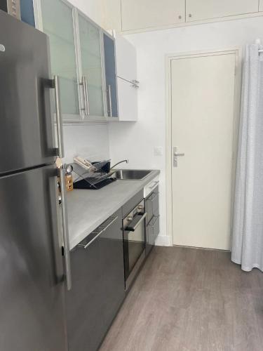 a kitchen with a sink and a refrigerator at Studio Vincennes centre in Vincennes