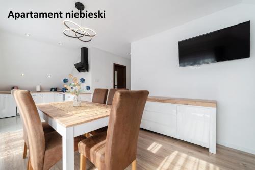 a kitchen and dining room with a wooden table and chairs at Apartamenty i Pokoje Gościnne Willa Dawid in Jastarnia