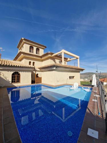 a villa with a swimming pool in front of a house at Villa los Dulces-Piscina Privada in Letur
