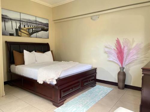 ein Schlafzimmer mit einem Bett und einer Vase mit einer Blume in der Unterkunft EliteStay at Casa De Barron in Kingston