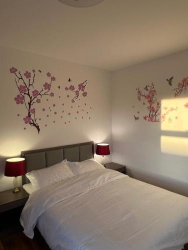 a bedroom with a white bed with flowers on the wall at Cromer House in Horsham Saint Faith