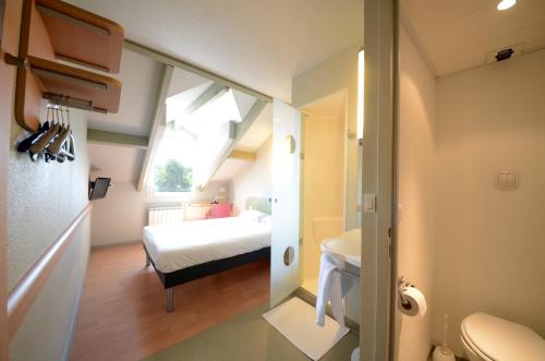 een kleine kamer met een bed en een badkamer bij ibis budget Brive La Gaillarde in Brive-la-Gaillarde