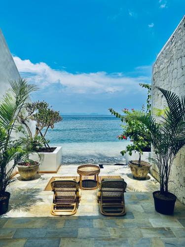 un patio con sedie, tavolo e vista sull'oceano di La Plage Onirique Beachfront Nusa Penida a Nusa Penida