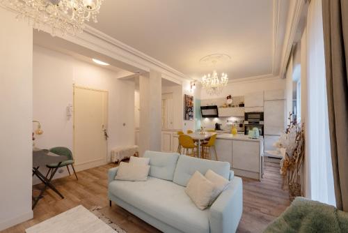 a living room with a white couch and a kitchen at L élégance toulousaine avec garage in Toulouse
