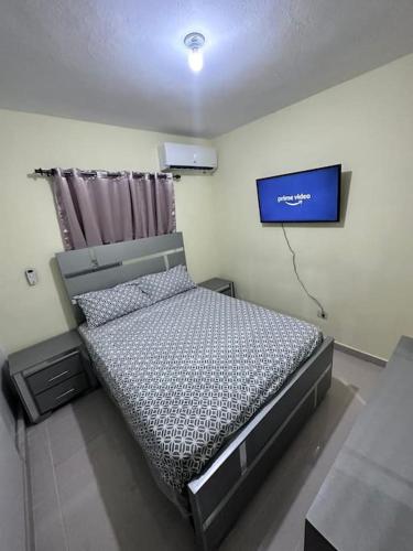 a bedroom with a bed and a tv on the wall at STD norte Apartamento Grande in Santo Domingo