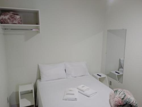 Una cama blanca en una habitación con cajas en Pousada Chácara VIVALLI en Holambra