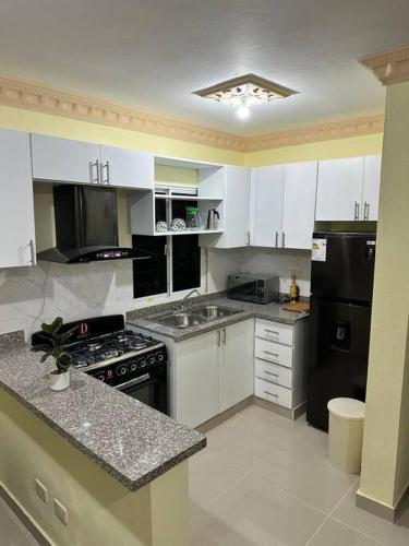 a kitchen with white cabinets and black appliances at STD norte Apartamento Grande in Santo Domingo
