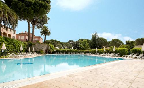 a large swimming pool with lounge chairs and trees at Hôtel Les Jardins De Sainte-Maxime in Sainte-Maxime