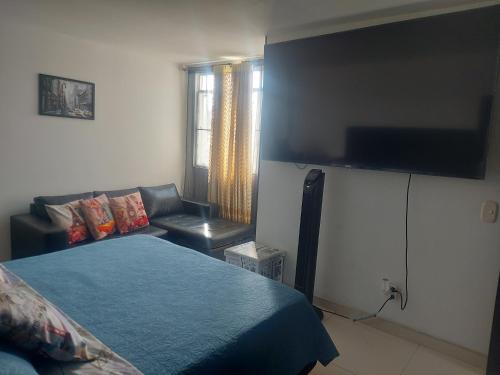 a bedroom with a bed and a couch and a flat screen tv at RentafrankitoS Ibagué TOP in Ibagué