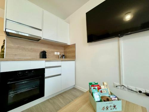 a kitchen with white cabinets and a black oven at Magic Appartement Disneyland in Serris