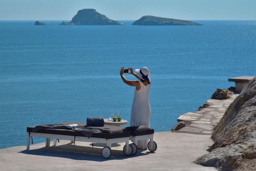 a woman taking a picture of the ocean at Onar Suites & Villas in Karavostasi