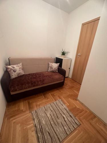 uma sala de estar com um sofá e um piso de madeira em Apartman Edita em Sarajevo
