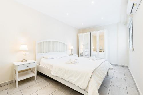 a white bedroom with a white bed and a mirror at Sunrise Horizon in Torrevieja