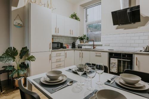 BlueSeaView Apartment with fabulous sea views في نيوكاسل: مطبخ مع طاولة مع الأطباق وكؤوس النبيذ