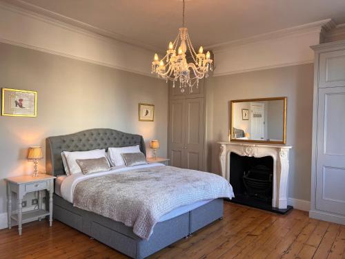 a bedroom with a bed with a fireplace and a chandelier at No2 Clarence grade II Regency townhouse short walk to racecourse and town centre in Cheltenham