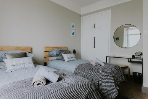 a bedroom with two beds and a mirror at BlueSeaView Apartment with fabulous sea views in Newcastle