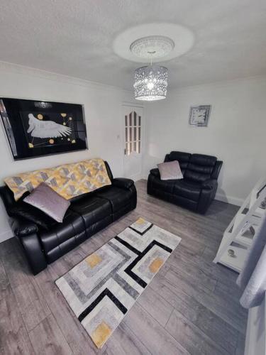 uma sala de estar com um sofá de couro preto e uma cadeira em Rise at the International Wall Belfast em Belfast
