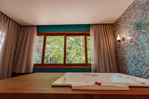 Schlafzimmer mit Badewanne und Fenster in der Unterkunft Resende Imperial Hotel & Spa in Itacaré