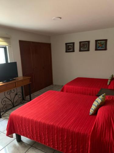 1 dormitorio con 2 camas rojas y TV en Suites La Jolla, en Lima del Alto