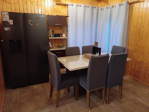 a kitchen with a table and chairs and a refrigerator at Cabaña ñandú in Cochrane