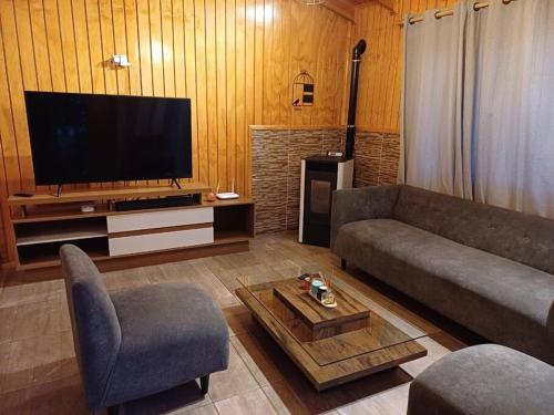 a living room with a couch and a tv at Cabaña ñandú in Cochrane