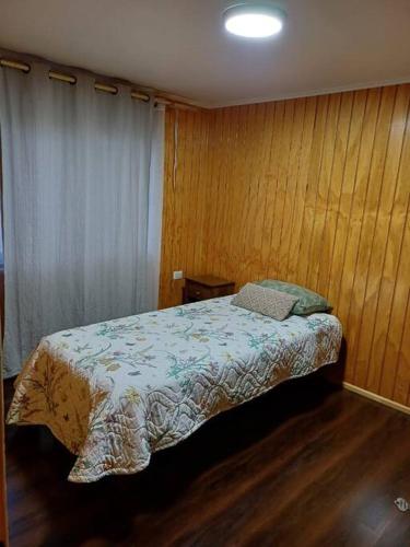 a bedroom with a bed with a wooden wall at Cabaña ñandú in Cochrane