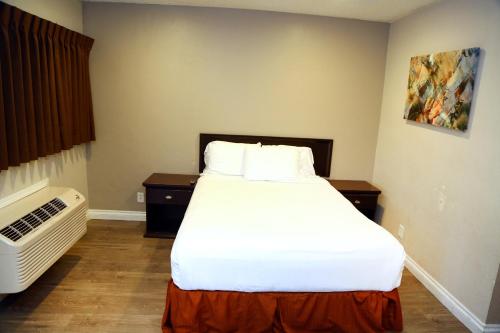 a bedroom with a large white bed in a room at Anaheim Executive Inn & Suites in Anaheim