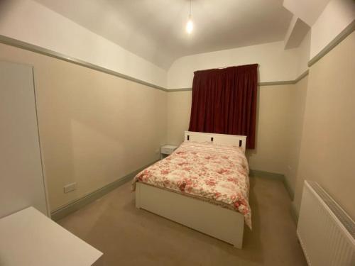 2 Bed House in Barrow Hill Sleeps 4 في Hollingwood: غرفة نوم صغيرة بها سرير ونافذة حمراء