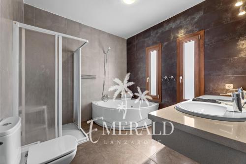 a bathroom with a tub and a toilet and a sink at Casa del Mar - Piscina y Jacuzzi Privado in Costa Teguise