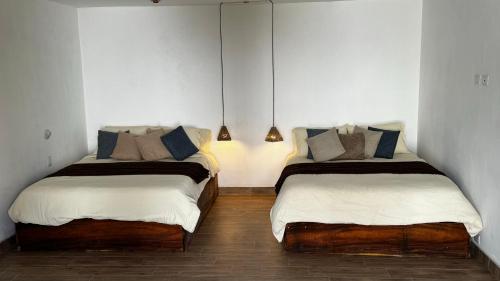 two beds in a room with white walls at Taura in Antigua Guatemala