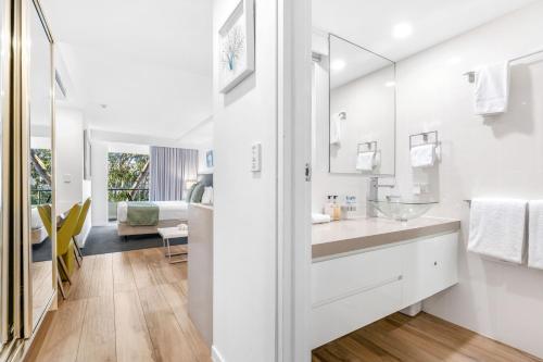uma casa de banho branca com um lavatório e um espelho em Wantima Hastings St Studio em Noosa Heads