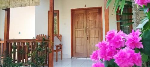 a front door of a house with pink flowers at Bungalow And Restaurant Anda in Kuta Lombok