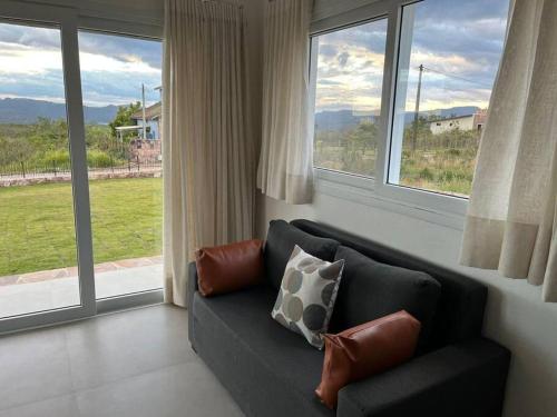 a black couch in a living room with large windows at Casa na Montanha (Mucugê/Bahia) in Mucugê