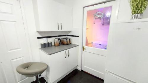 a small kitchen with white cabinets and a door at Central Haven-5bedroom Great For Longer Stays In Canterbury kent!!! in Kent