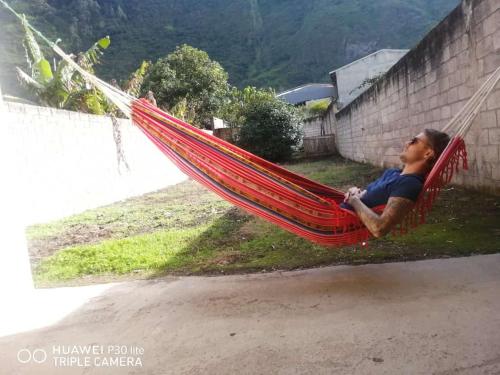 un uomo sdraiato su un'amaca rossa di CASA DE LINDA a Baños